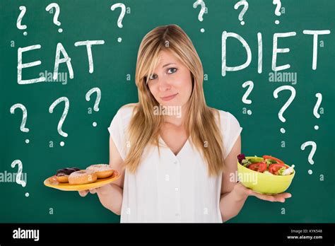 Confused Young Woman Making Choice To Eat Healthy And Unhealthy Food