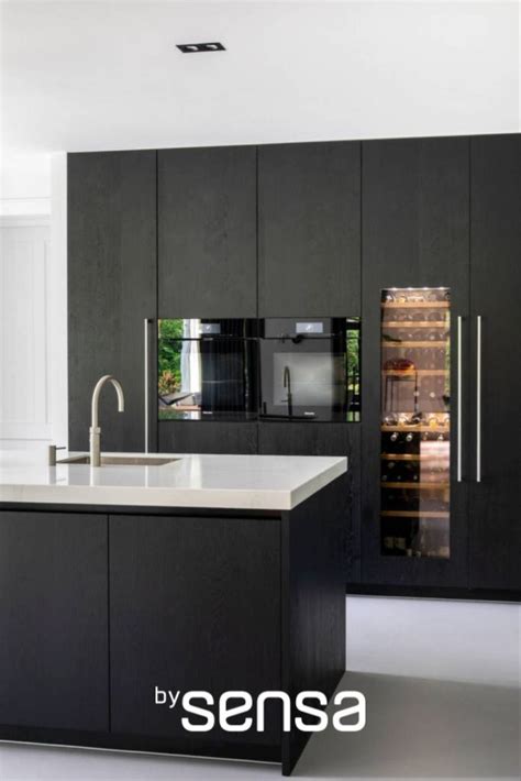 A Modern Kitchen With Black Cabinets And Stainless Steel Appliances