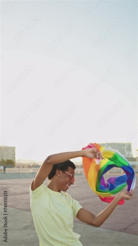 Vídeo do Stock Vertical video of a cheerful African American gay man dancing with rainbow LGBT