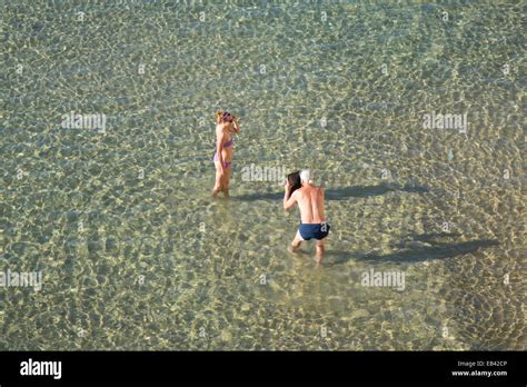 Benidorm Costa Blanca Spain Europe Man In Sea Shooting Woman In Bikini With Tablet Stock