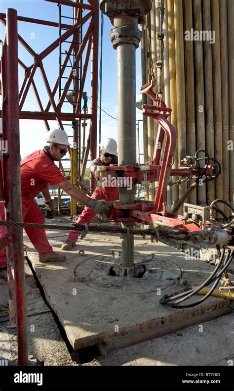 Onshore Oil And Gas Exploration Rig Site With Crewmen Connecting Casing