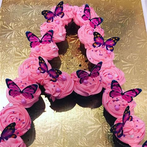 Cupcakes With Pink Frosting And Purple Butterflies Arranged In The