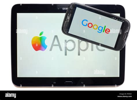 The Google logo on a smartphone and Apple on a tablet photographed ...