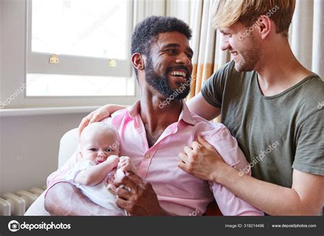 Loving Male Same Sex Couple Cuddling Baby Daughter Sofa Home Stock Photo Monkeybusiness