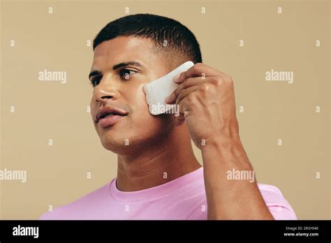 Male Model Using A Gua Sha Stone On His Face A Traditional Massage