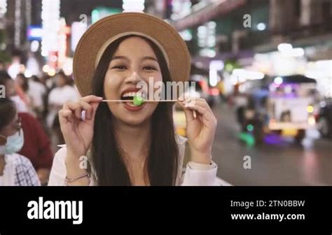 Asian Woman Enjoying And Eating Street Food In Night Market With Crowd