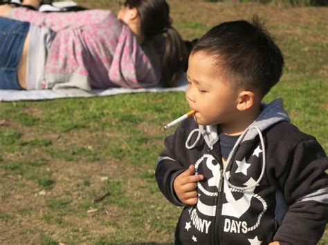 This Is A Chinese Baby Smoking Cigarettes In A Park