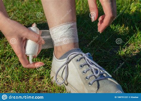 Stretching The Ankle A Woman Bandages Her Leg While Walking In Summer