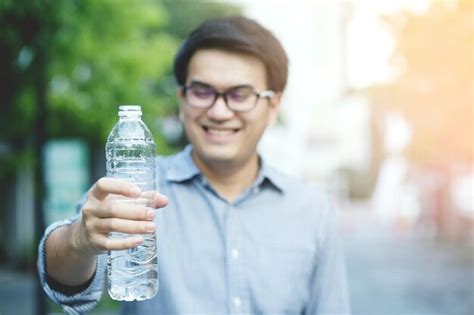 Premium Photo Smiling Man Holding Water Bottle Outdoors