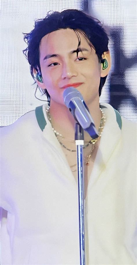 A Man With Black Hair And Piercings On His Ears Holding A Microphone In