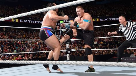 Two Men In Wrestling Stances On The Ropes With An Referee Watching Them