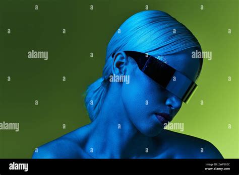 Extraordinary Blonde Woman With Sci Fi Robotic Sunglasses Posing In Blue Lights On Green