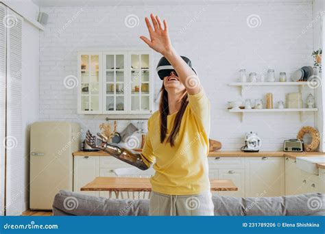 Woman With Bionic Arm And Vr Headset Dances In Kitchen Stock Photo