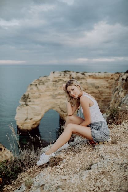 Free Photo Young Blonde Woman Sitting On The Rocks Top By The Ocean