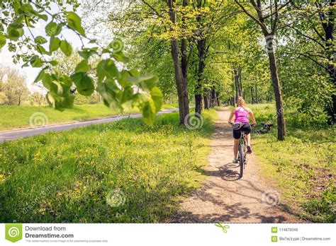 Woman Cycling A Mountain Bike In City Park Summer Day Stock Photo