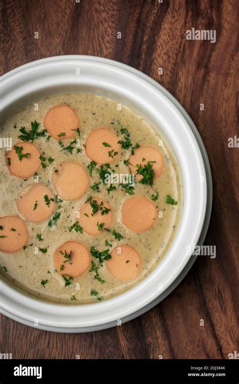 German Traditional KARTOFFELSUPPE Potato And Sausage Soup On Wood Table