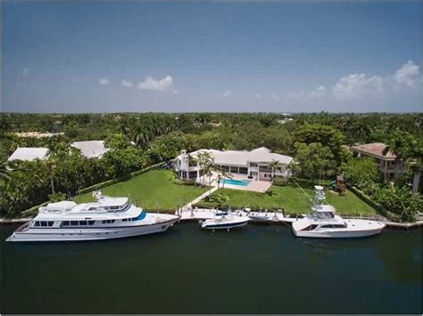 Two Yachts Are Docked In The Water Near A Large House With A Pool And