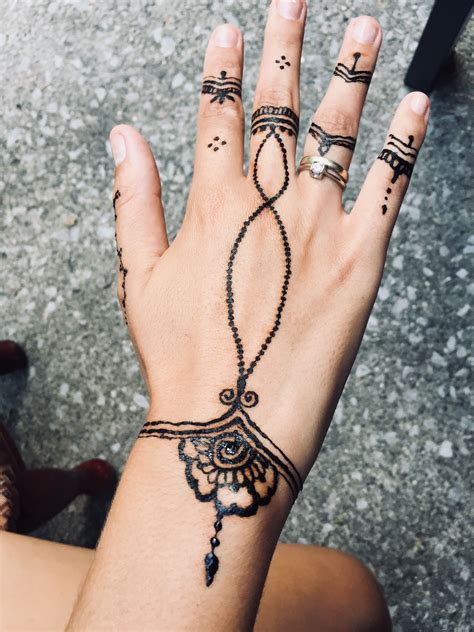 A Womans Hand With Tattoos On It And Two Rings Attached To The Wrist