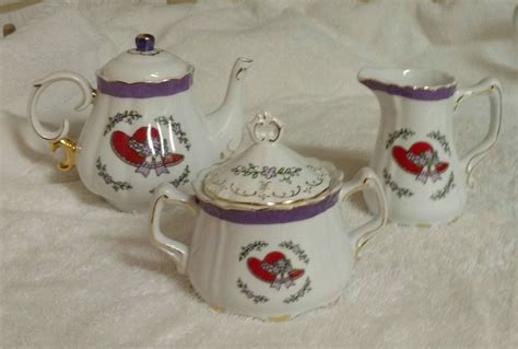 Three White Teapots With Red Hearts On Them Sitting Next To Eachother