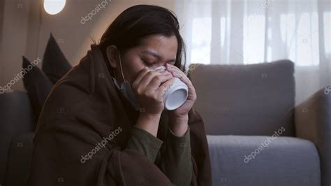 Mujer asiática enferma bebiendo agua tibia en tiempos de sufrimiento