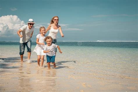 Família Feliz Que Está Na Praia No Tempo Do Por Do Sol Foto de Stock