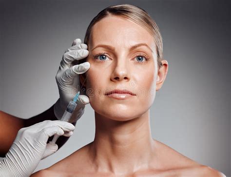Beautiful Mature Woman Getting Botox Injection In Studio Against A Grey Background Stock Image