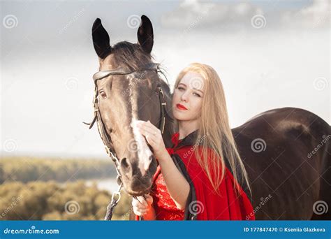 Girl Blonde With Long Hair With A Black Stallion In A Red Historical Stock Photo Image Of