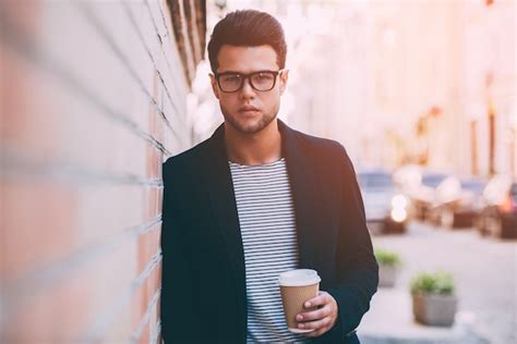 Hombre moderno apuesto joven en ropa casual elegante con taza de café