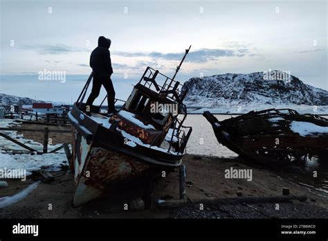 A Man Stands On An Old Wrecked Ship Against The Background Of A Sunset