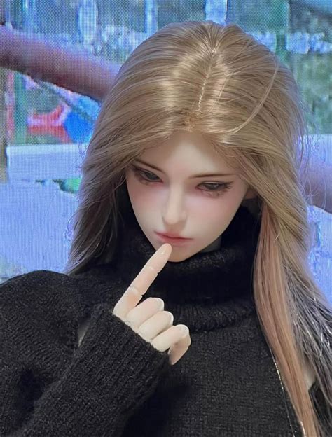 A Close Up Of A Doll Holding A Finger Near Her Mouth And Looking At The