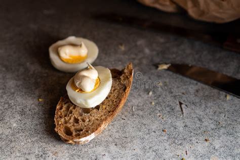 Halves Of Chicken Eggs With Mayonnaise And Brown Bread On A Dark