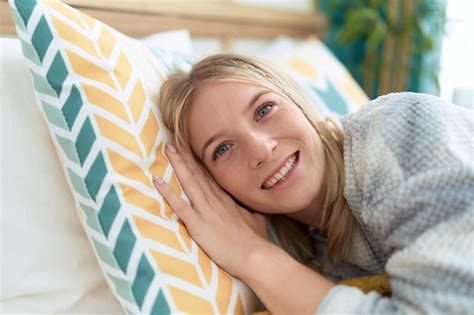Jeune femme blonde souriante confiante allongée sur le lit dans la chambre Photo Gratuite