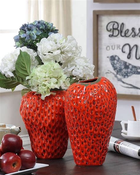 Two Red Vases Sitting On Top Of A Table Filled With White Flowers And Fruit