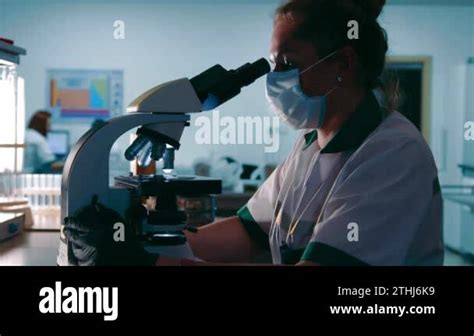 Scientist Researcher Examines Virus Samples Under A Microscope Female