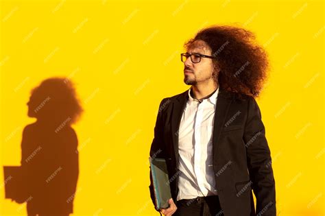 Premium Photo Businessman With Long Hair And Glasses Holding A Folder Over Yellow Background