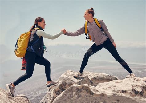 Happy Women Help While Hiking Up A Rocky Mountain In Nature With