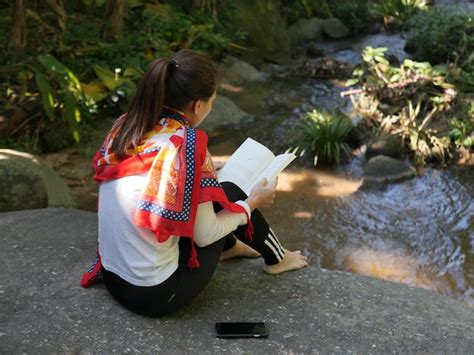 Premium Photo Rear View Of Woman Reading Book While Sitting By Stream