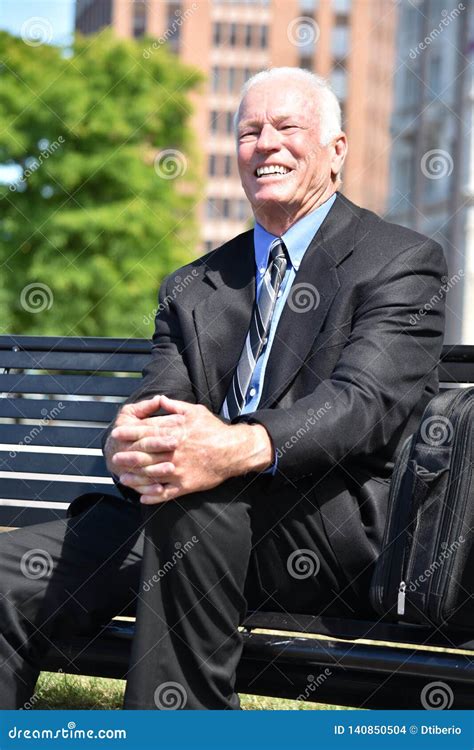 Smiling Adult Senior Business Man Wearing Suit And Tie Sitting On Bench