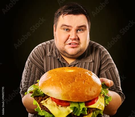 Man eating fast food hamberger. Fat person made great huge hamburger and admires him, intending ...