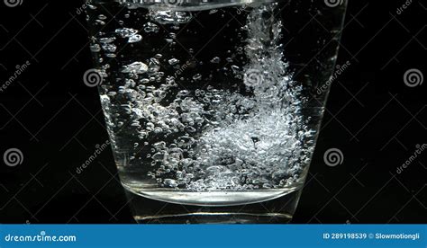 Water Being Poured Into Glass Against Black Background Stock Image