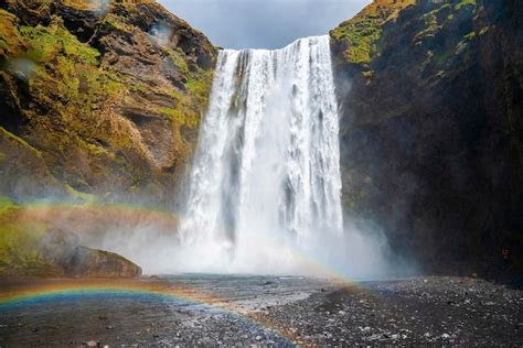 Vista de ângulo baixo de lindos arco íris e cachoeira skogafoss caindo