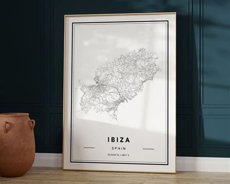 A Framed Poster With The Name And Map Of Ibiza Spain In Front Of A Vase