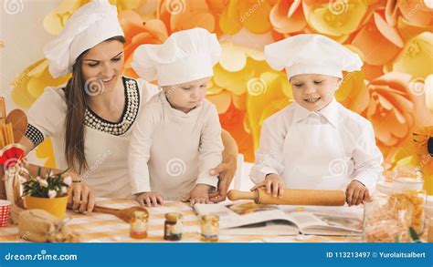 Madre Feliz Con Los Niños Que Preparan La Cena En La Cocina Imagen de