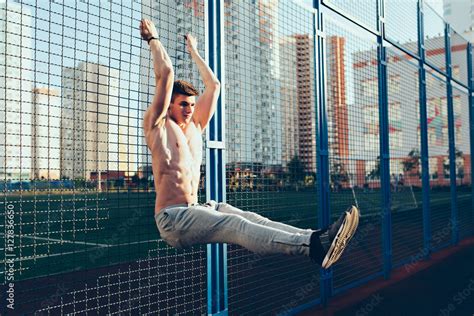Full Length Photo Of Tense Guy With Naked Muscular Body At Workout Training On Fence In The