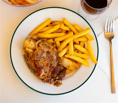 Costra De Cerdo Al Horno Con Plato De Patatas Fritas Foto De Archivo