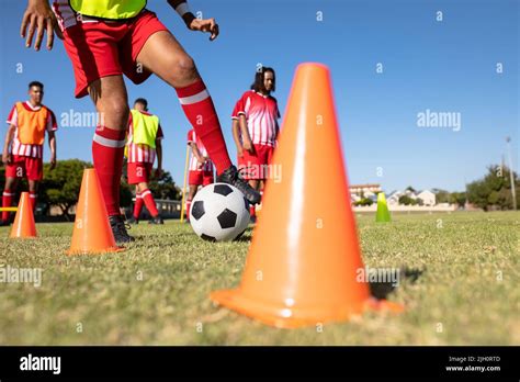 Multiracial Male Soccer Players Dribbling Ball Between Oranges Cones