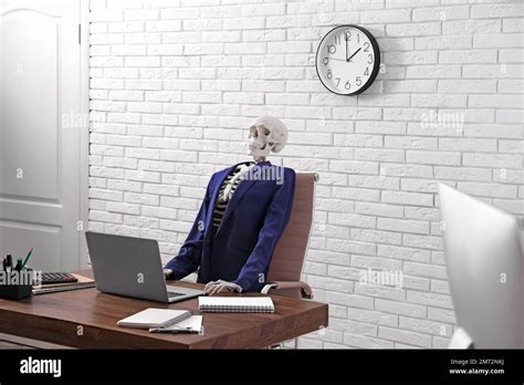 Human Skeleton In Suit Using Laptop At Table In Office Stock Photo Alamy