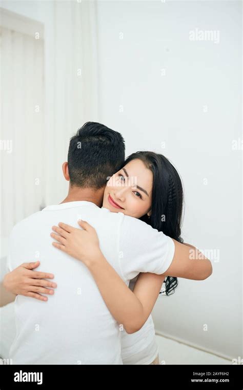 Young Couple In The Bedroom Side View Of Unfaithful Man And Woman Are Cheating While Hugging