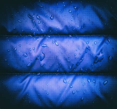 A Close Up Of Blue Waterproof Rain Jacket Fabric With Water Droplets