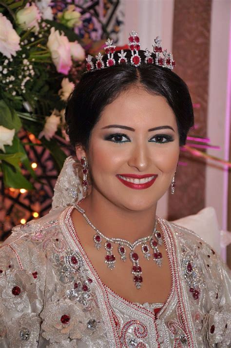 A Woman Wearing A Tiara Sitting In Front Of A Flower Arrangement And